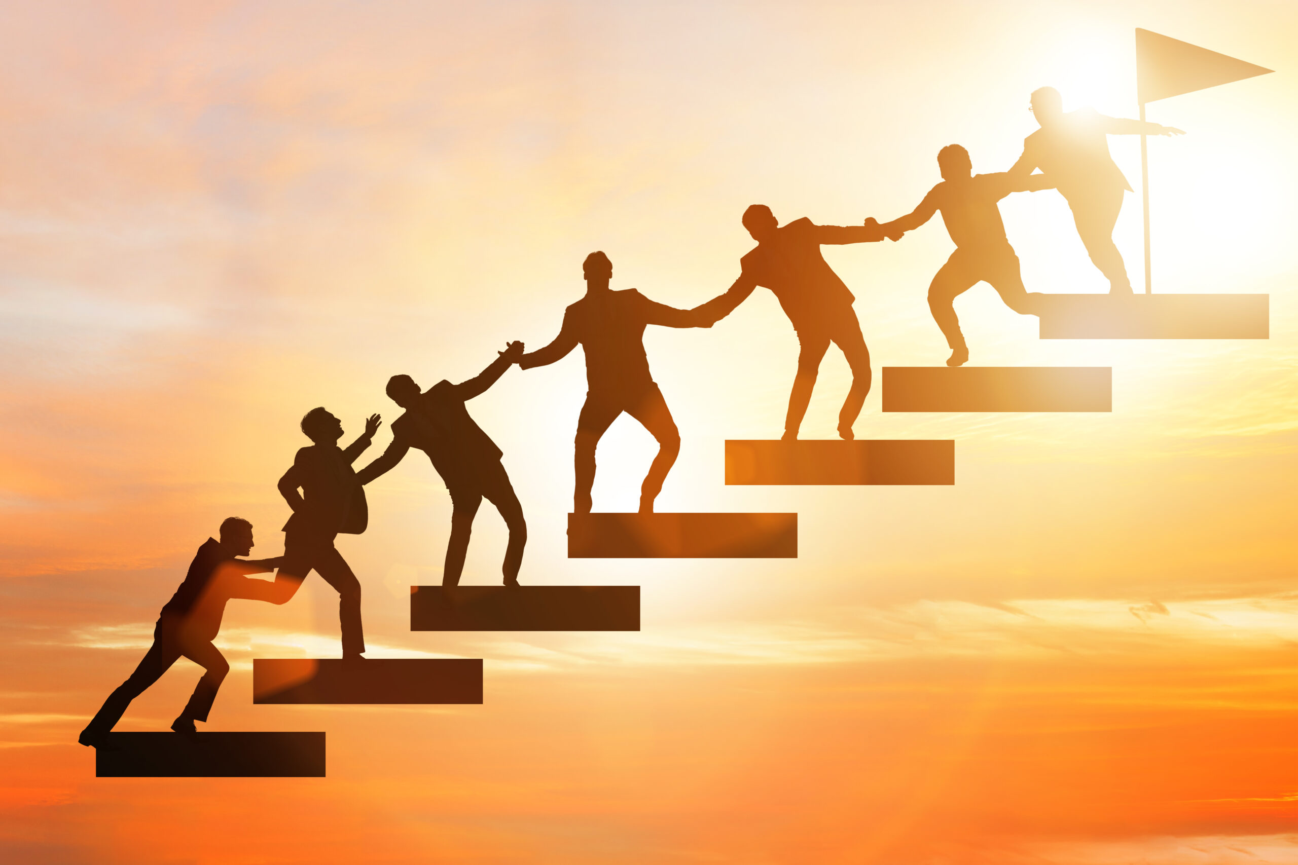 Silhouettes of people climbing stairs, helping each other toward a flag at the top under a golden sunset sky, symbolize teamwork and The Mentorship Guidance and Decision-Making Process—highlighting selecting a mentor who doesn’t take over but supports success.