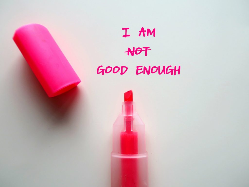 A pink highlighter with its cap off lies on a white surface. Next to it, the words I am not good enough are written, with not crossed out in pink—capturing A Guide to Empowerment and Success and how to break free from self-sabotage.