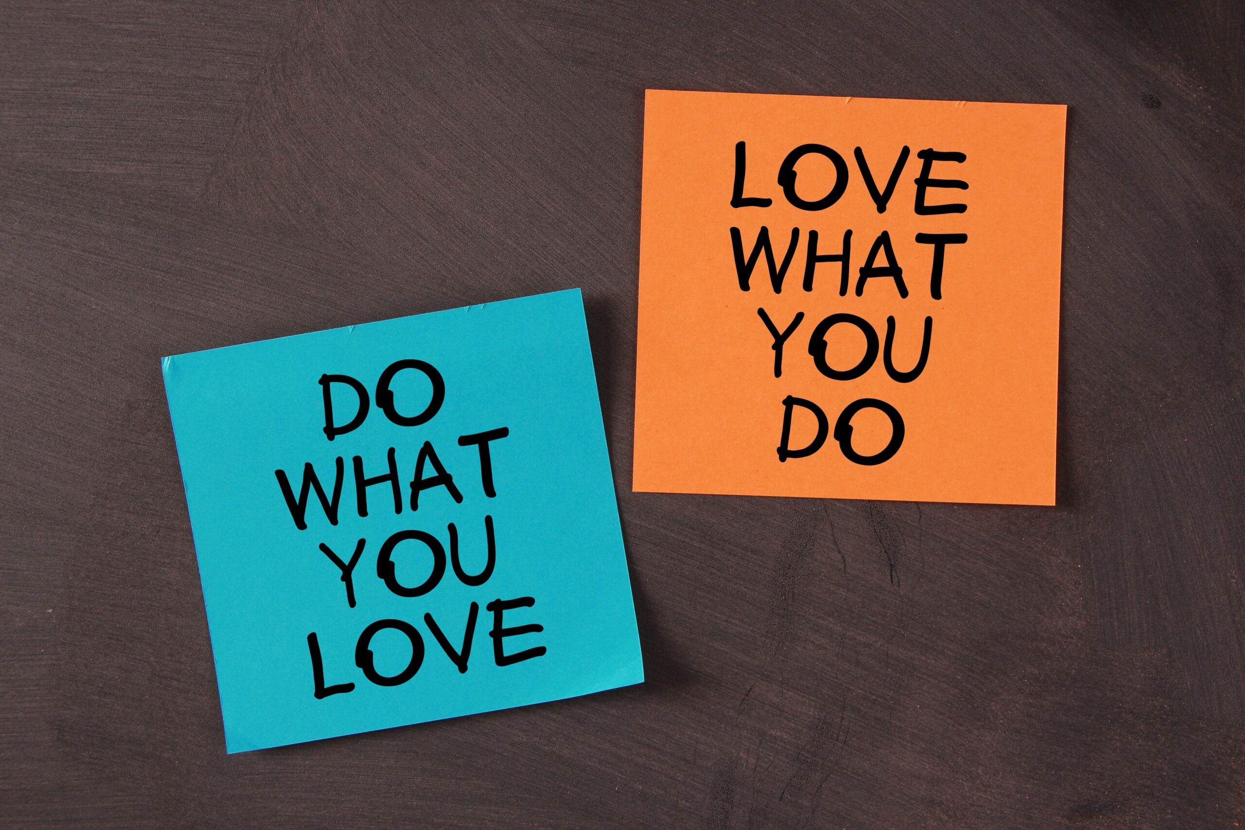 Two sticky notes on a dark surface: one blue note reads DO WHAT YOU LOVE, and one orange note reads LOVE WHAT YOU DO—perfect reminders for balancing passion and practicality every day.