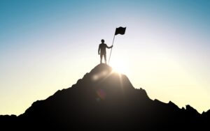Man standing on top of a mountain, holding a flag.