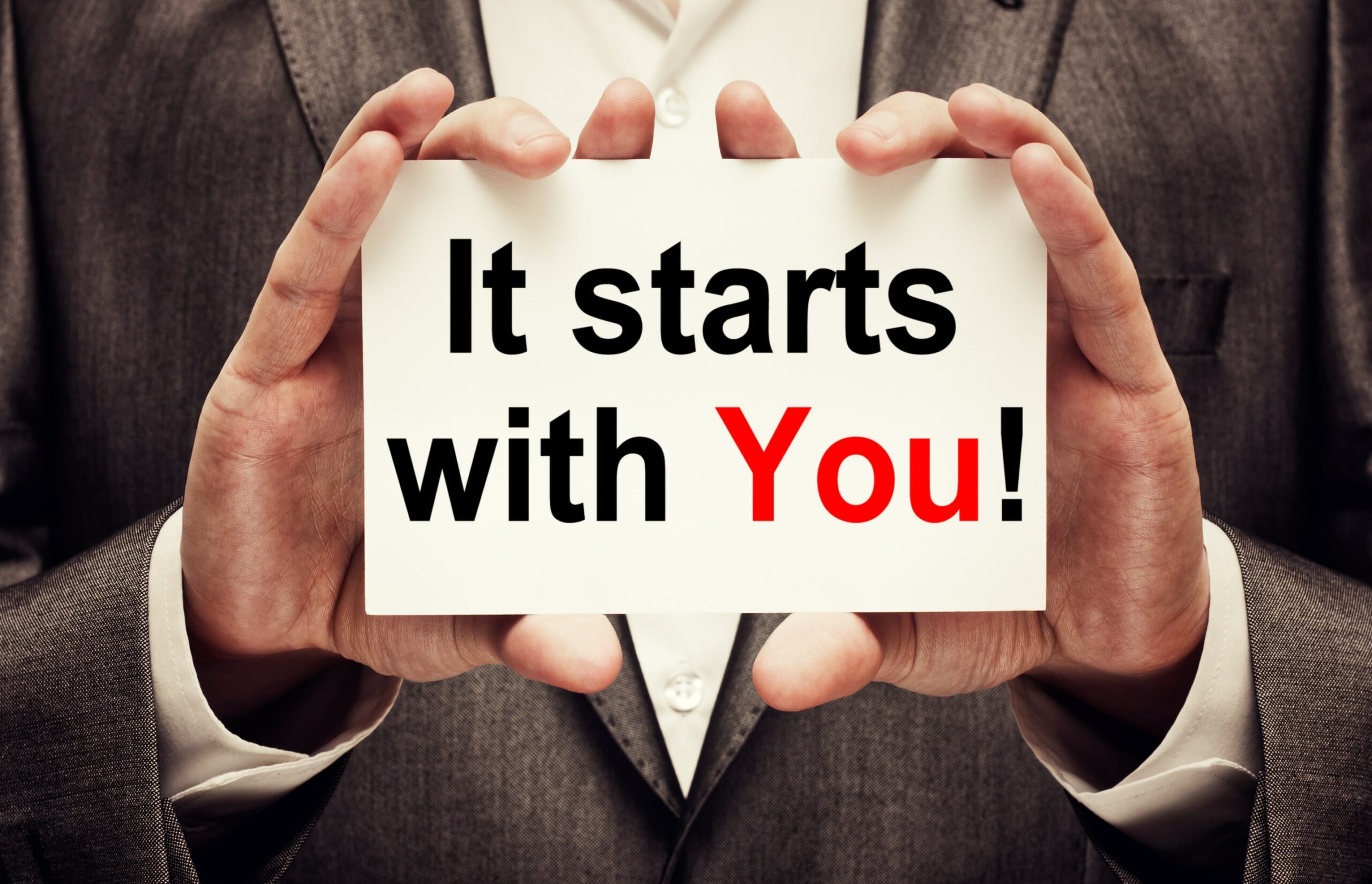 Business man holds up motivational sign.