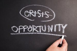 crisis and opportunity written on black chalkboard. crisis crossed out and opportunity underlined.