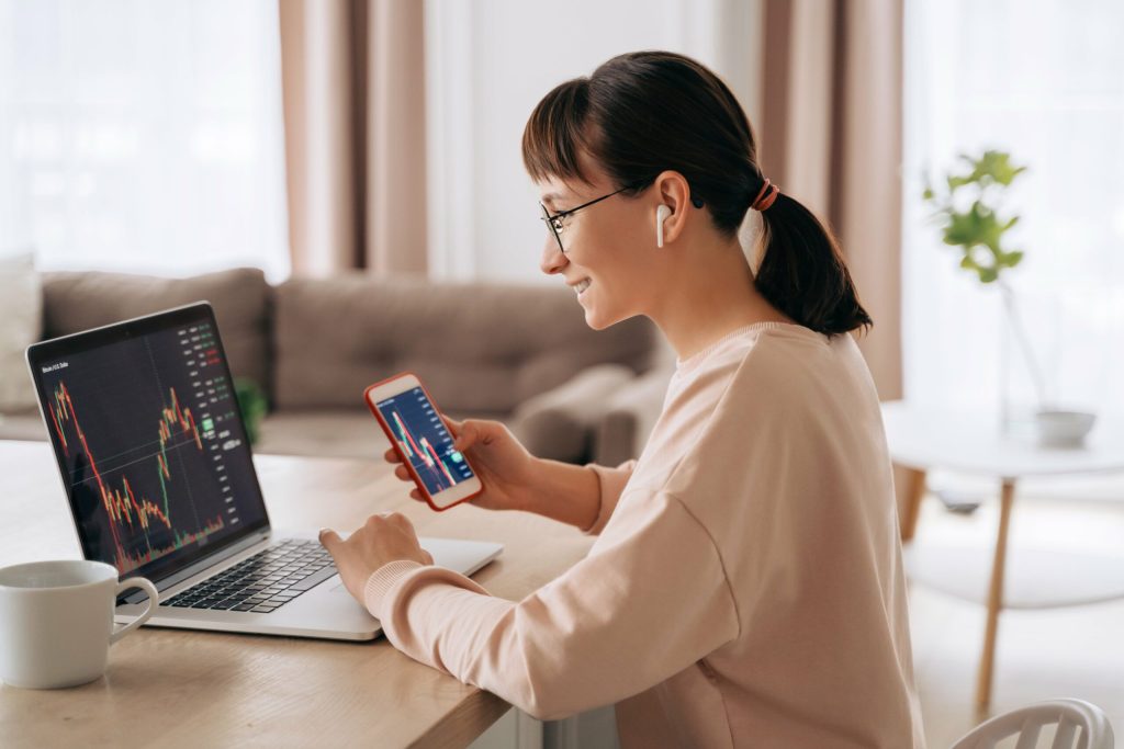 Women sitting at her desk looking at her laptop displaying a trading line graph