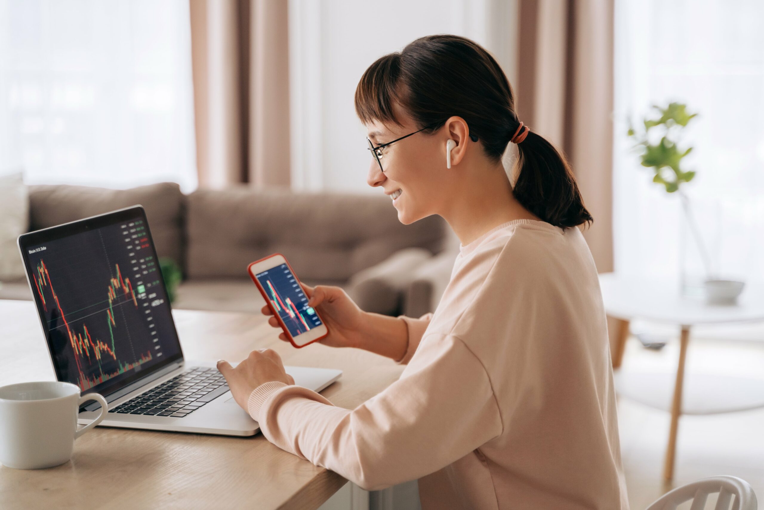 Women sitting at her desk looking at her laptop displaying a trading line graph