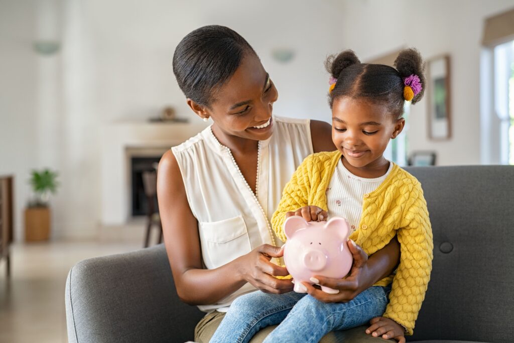 Mother and child holding pink piggy bank