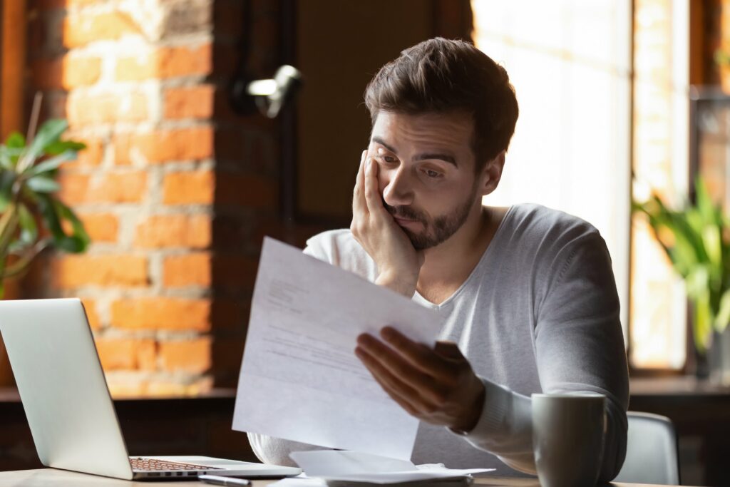 man looks over finances with worried expression