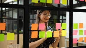 Woman in office sticking post-it notes to wall.