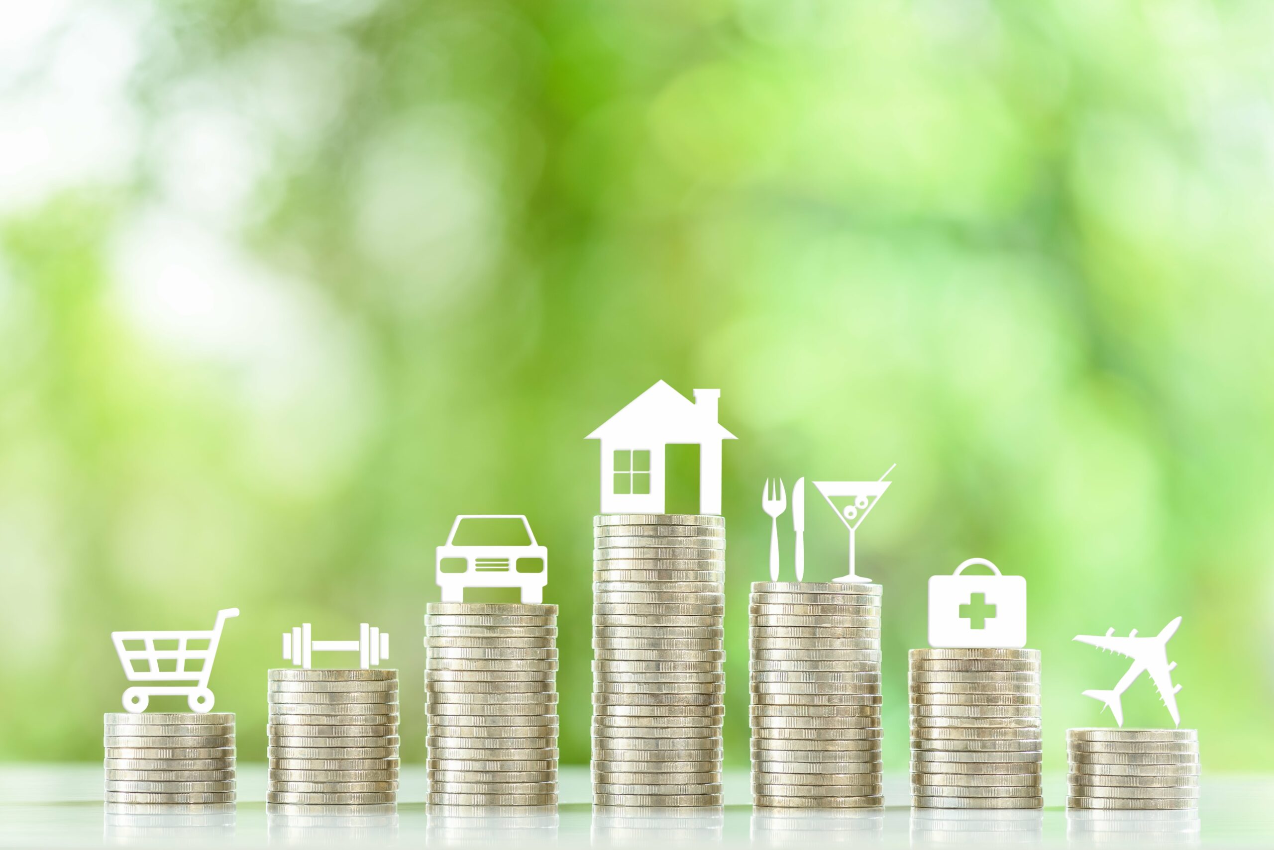 Stacks of coins with white icons on top, representing expenses like shopping, fitness, car, house, dining, healthcare, and travel—offering visual insights for Personal and Business Budget Tips against a blurred green background.