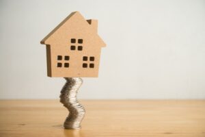 Modern house on unstable stack of coins