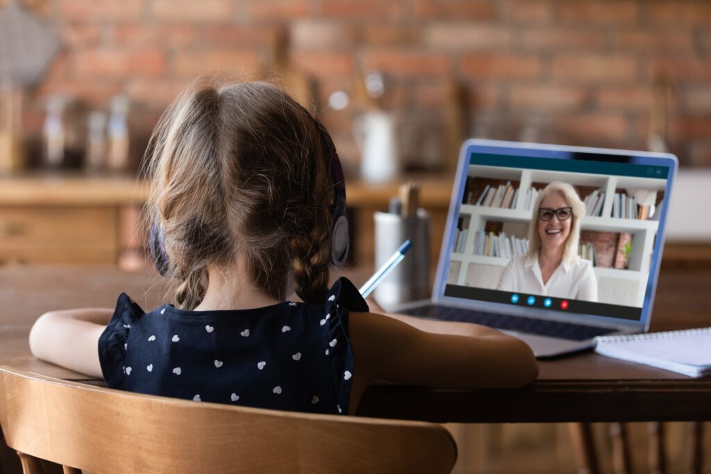 A girl holding a pen while on a Zoom call with an older woman.