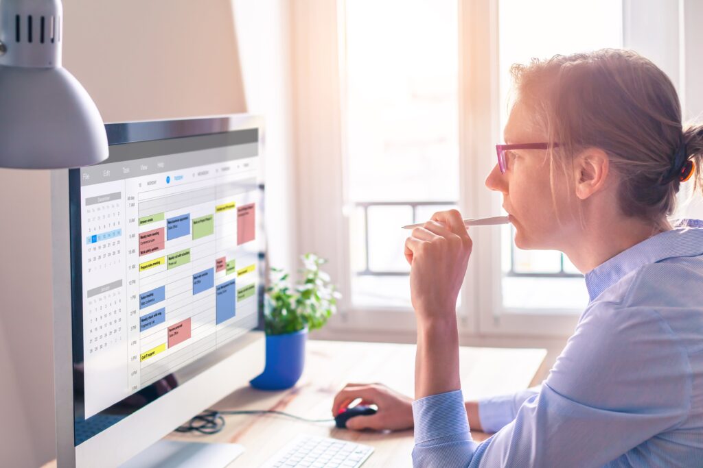 A woman sitting at her desk looking over her full calendar