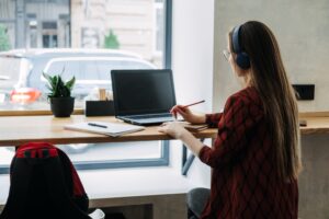 A woman working at a coffee shop with headphones on. 