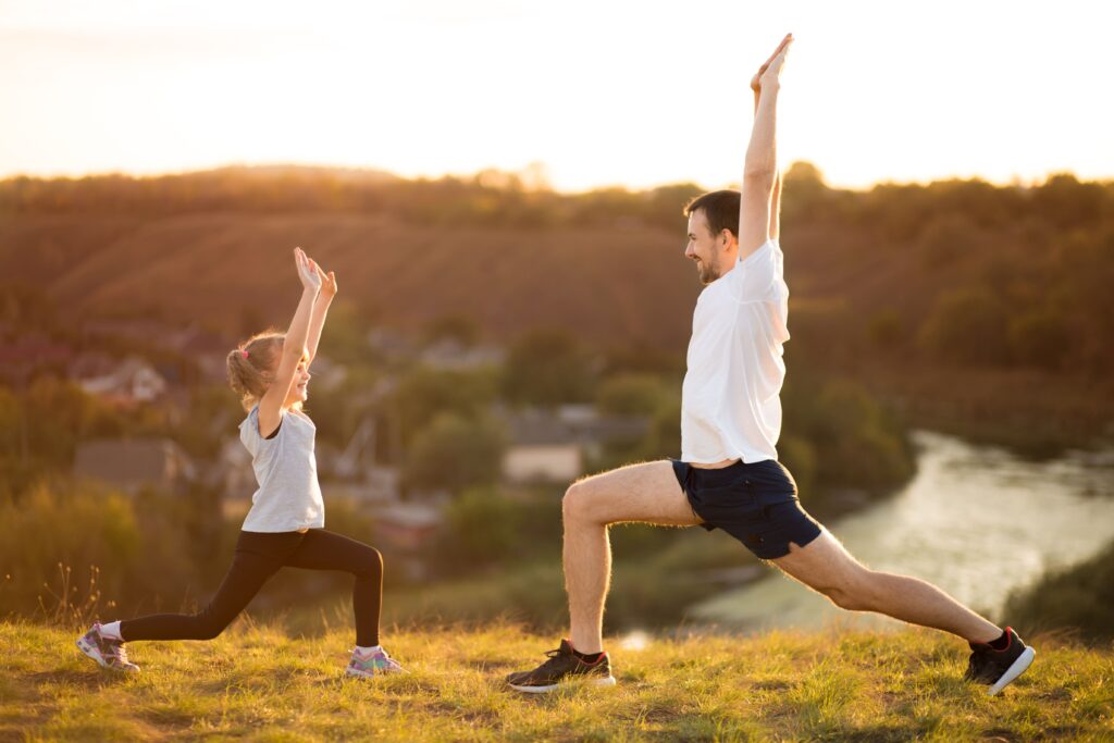 A father and daughter practicing a yoga stretch together