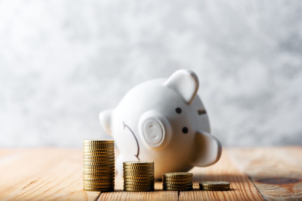 stacks of coins growing shorter in succession with a sad piggy bank on it's side in the background