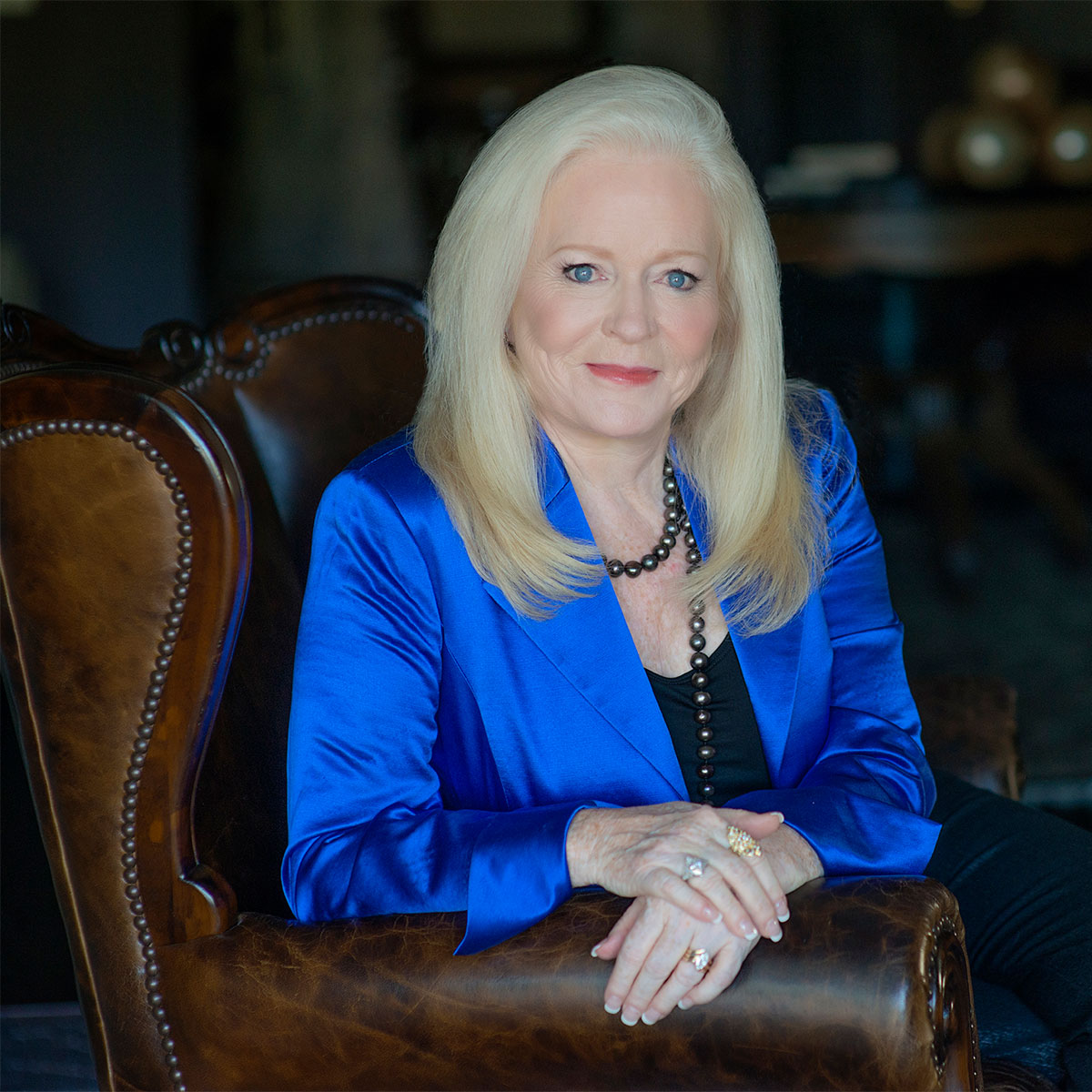 Sharon Lechter sitting on a brown leather couch in a blue blazer