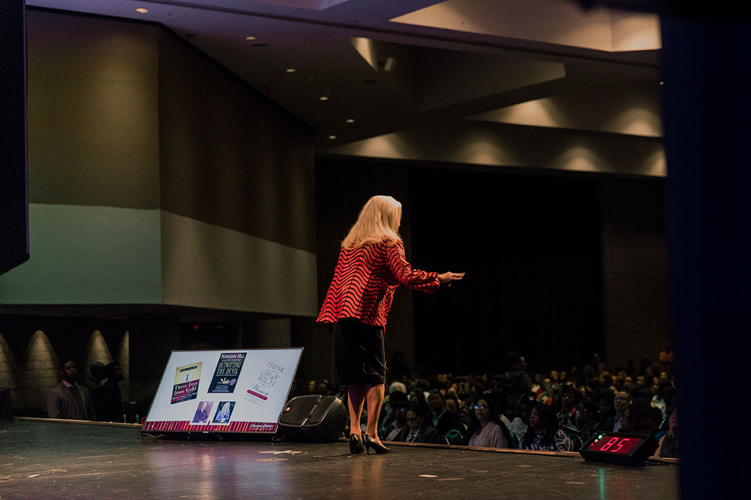 Sharon Lechter speaking to an audience standing at center stage