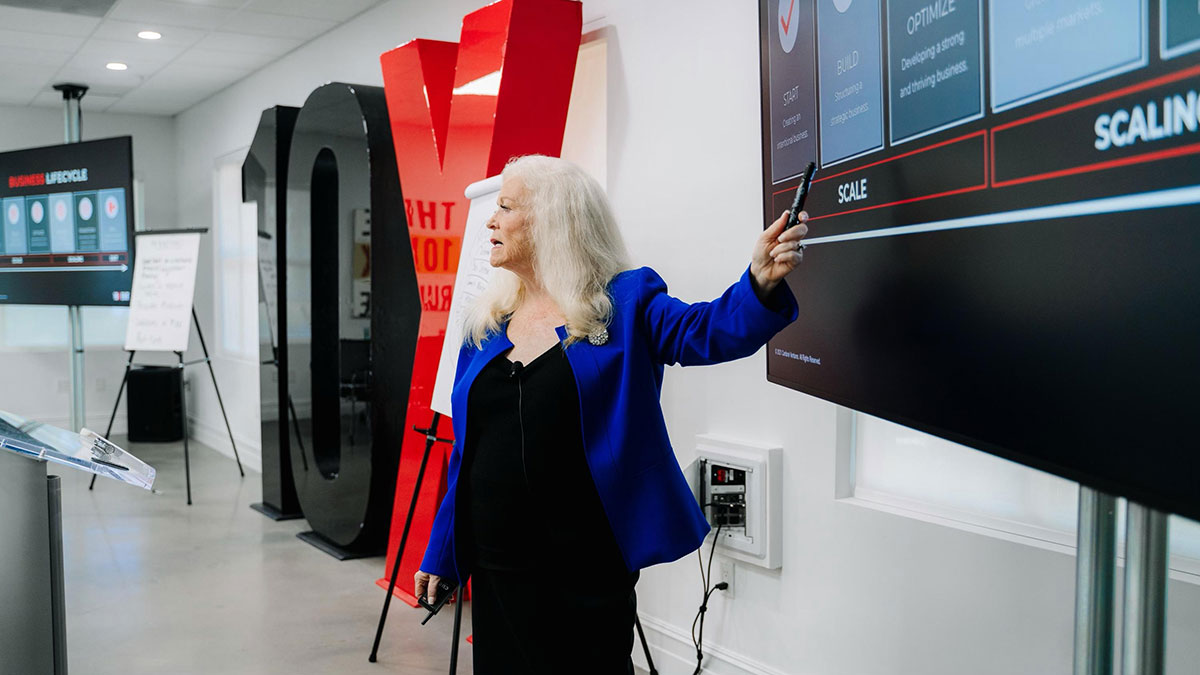 Sharon Lechter pointing to a powerpoint presentation at her group mastermind session