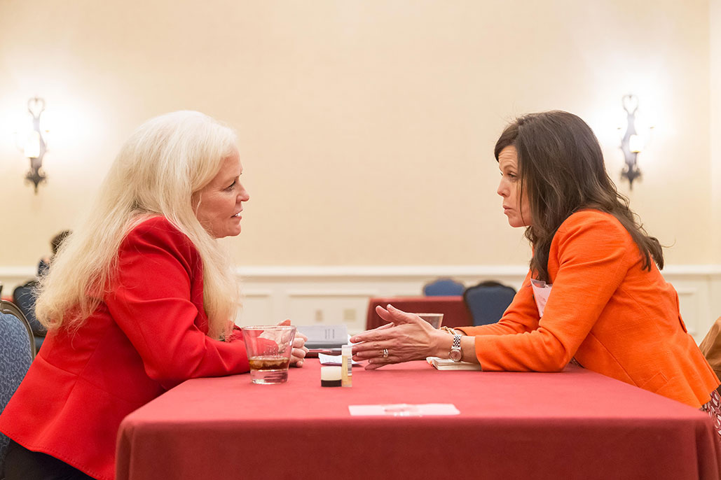 Sharon Lechter in a red blazer speaking to and mentoring a woman in a orange blazer