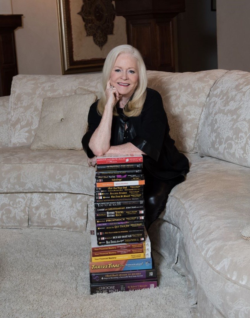 Sharon Lechter showcasing all of her books as they are stacked in front of her