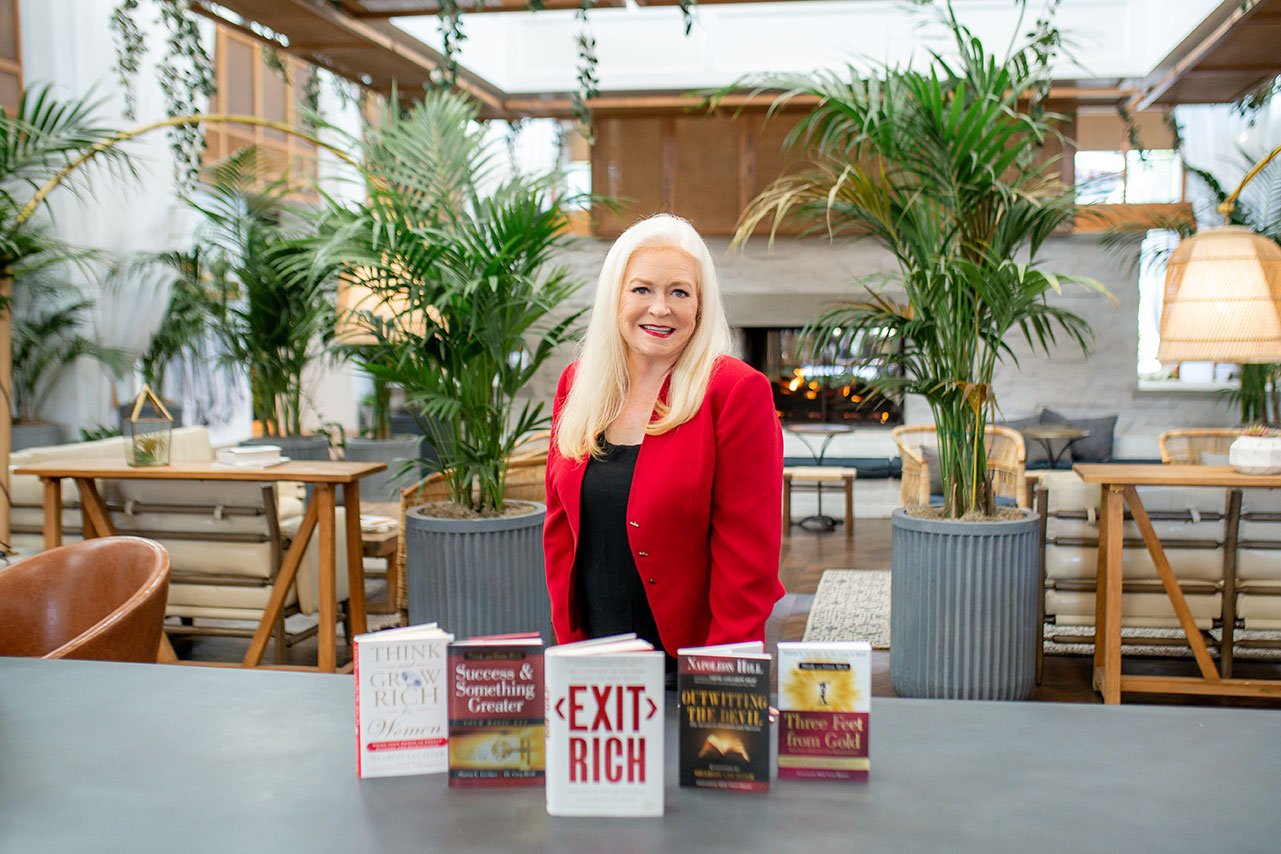 Sharon Lechter wearing a red blazer showcasing her books