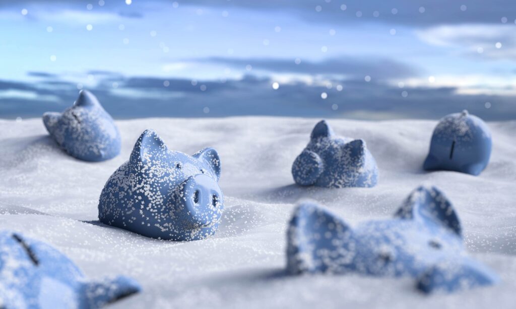 Blue piggy banks partially buried in snow, scattered across a snowy landscape under a cloudy sky with falling snowflakes.